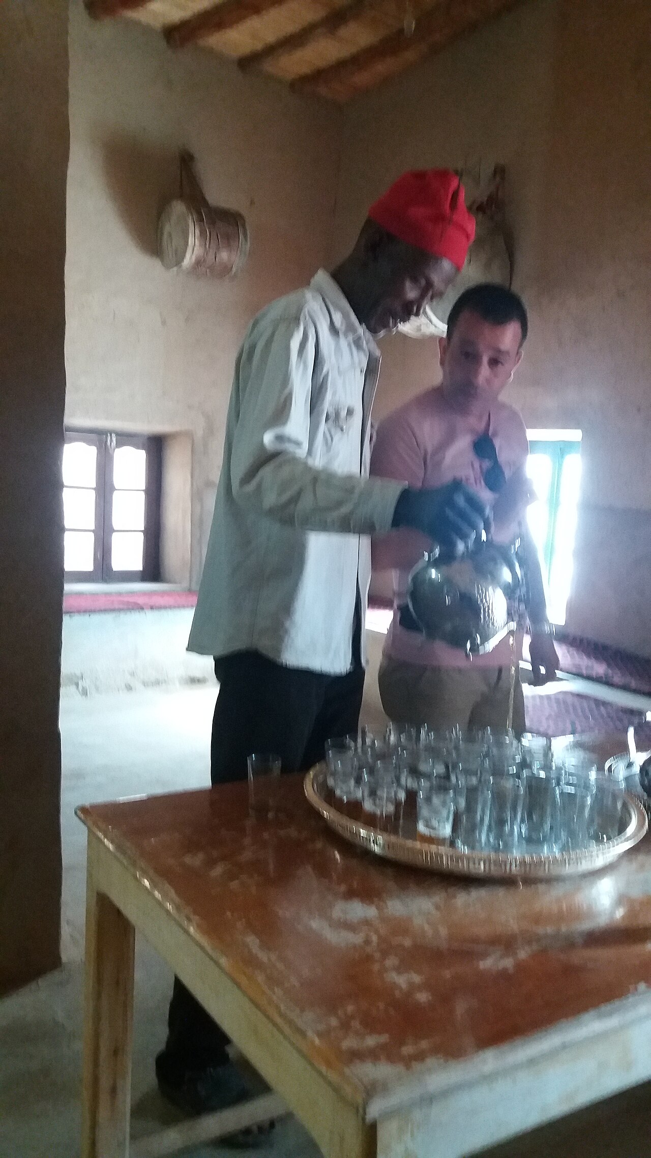 رجل يصبّ الأتاي المغربي من إبريق مرتفع فوق الكأس